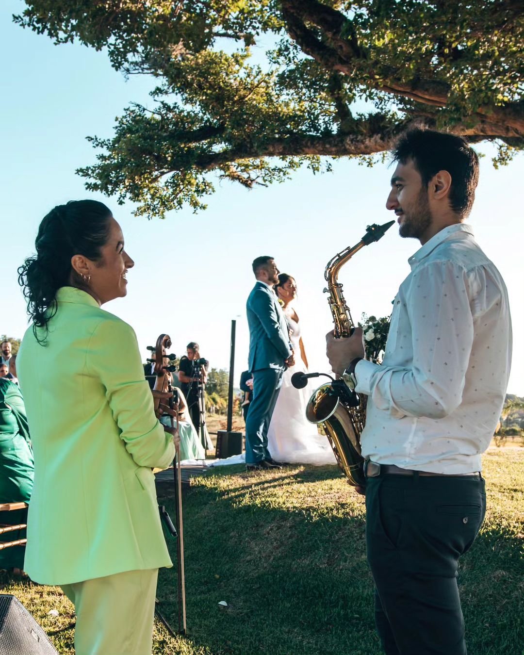 Augusto Santos no sax e violinista tocando em cerimônia de casamento ao ar livre